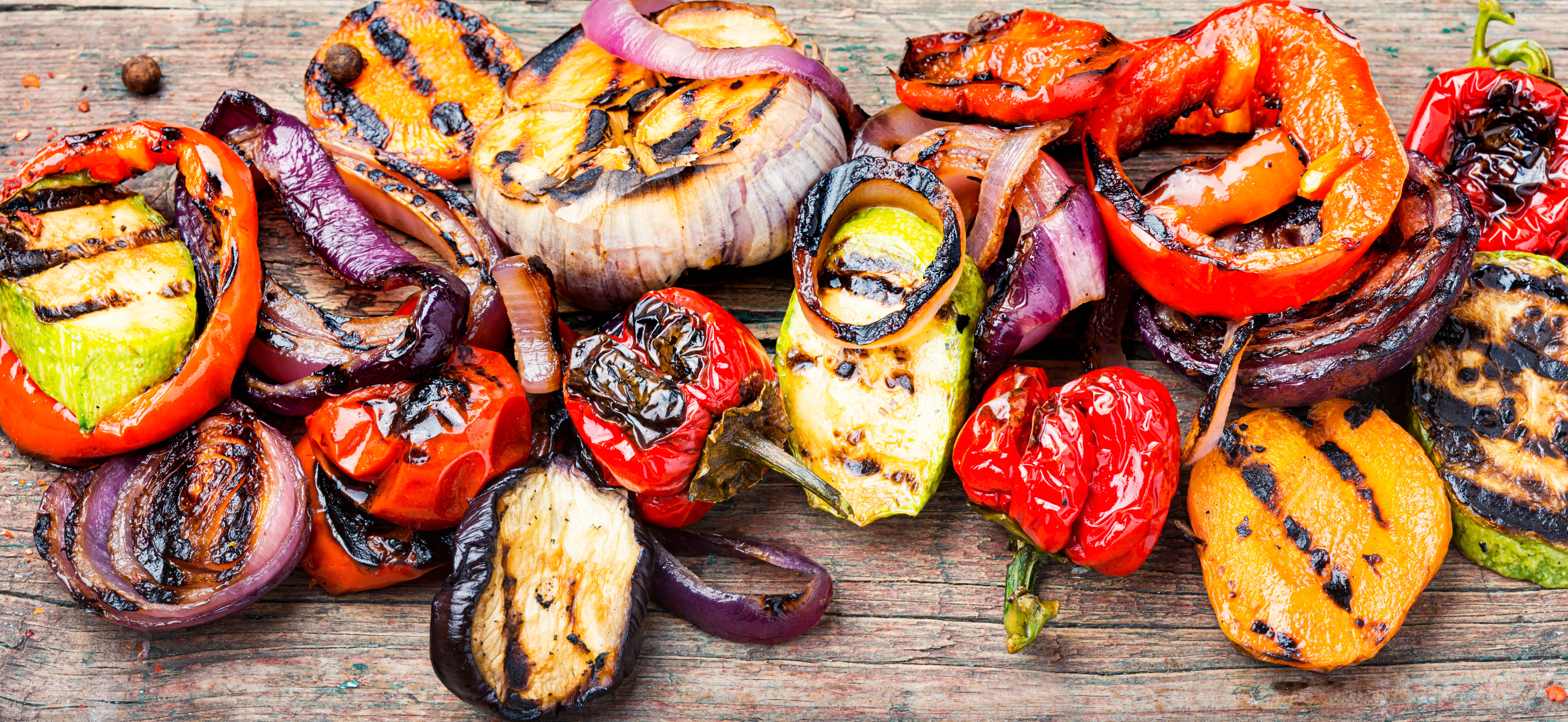 Cutting board filled with grilled vegetables - including tomatoes, peppers, onions, zucchini, and more